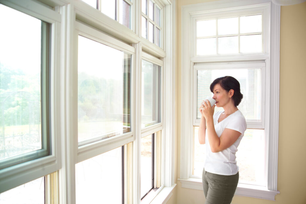 woman looking out of her home windows