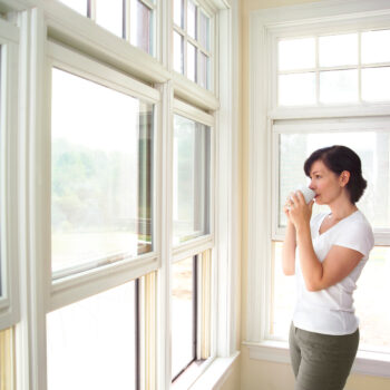 woman looking out of her home windows