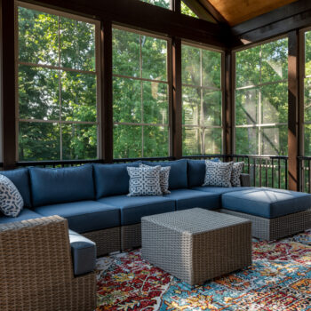 A new porch enclosure with big glass windows and a sofa with blue cushions