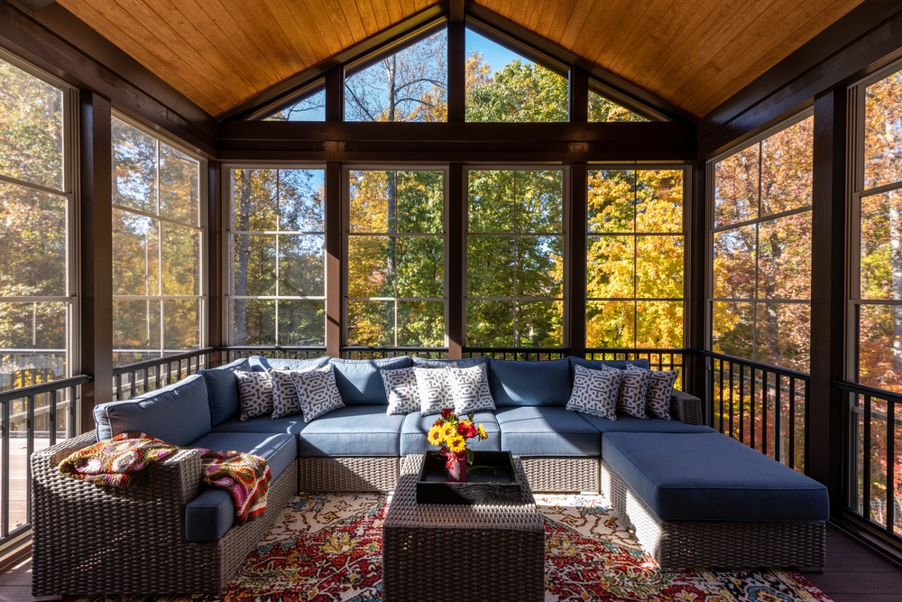 A porch enclosure with fall foliage in the background