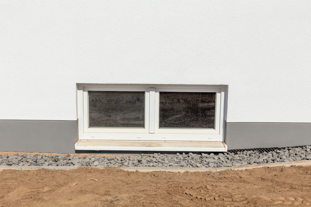 Closeup of a basement hopper window from the outside